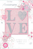 This anniversary card, imagined as part of a Whitechapel florist's display, offers a gentle, romantic tribute to enduring love. At its heart, the word "LOVE" becomes both message and artwork, with each letter softly raised and coated in fine, velvety glitter. The tones are tender-silvery pinks and pearlescent whites-with the letter "O" replaced by a shimmering heart motif, richly textured in silver. This central design rests on a blush panel, set slightly apart from the pale pink background so it seems to gently float, much like a featured bloom emerging from an anniversary bouquet prepared for a home near Altab Ali Park. Around this focal point, the card blossoms into a soft halo of flowers. Petals in blush, mauve, and gentle rose are painted with almost watercolour softness, their edges blending into the background yet defined by elegant line work. Fine swirls and decorative curls weave between the blooms, suggesting movement and the lightness of an English spring garden after rain, while tiny petals and discreet butterfly shapes add a sense of whimsy. The texts "On Our Anniversary" and "I love you today and always" appear in a refined script, delicate and sincere, reminiscent of handwritten notes accompanying fresh stems. Subtle shading beneath some elements creates depth, letting the flowers and letters appear layered rather than flat. The overall effect is tender and intimate, like a keepsake card meant to sit beside fresh anniversary flowers delivered across Whitechapel-a soft-spoken yet deeply heartfelt celebration of a shared journey.